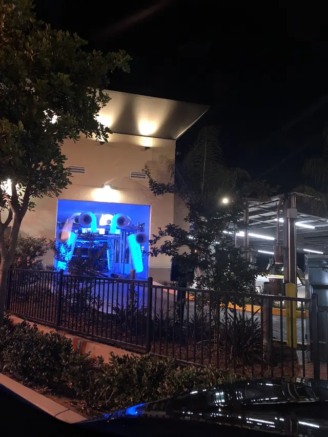 The tunnel at night, lit blue from inside, behind the fence and palms